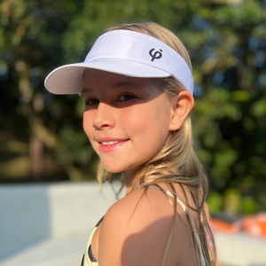 Niña deportista usando visera blanca Frouros de perfil, accesorio cómodo y ajustable para días de sol y entrenamiento.