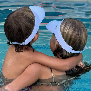 Niños usando viseras Frouros en la piscina, material de secado rápido ideal para natación y juegos acuáticos.