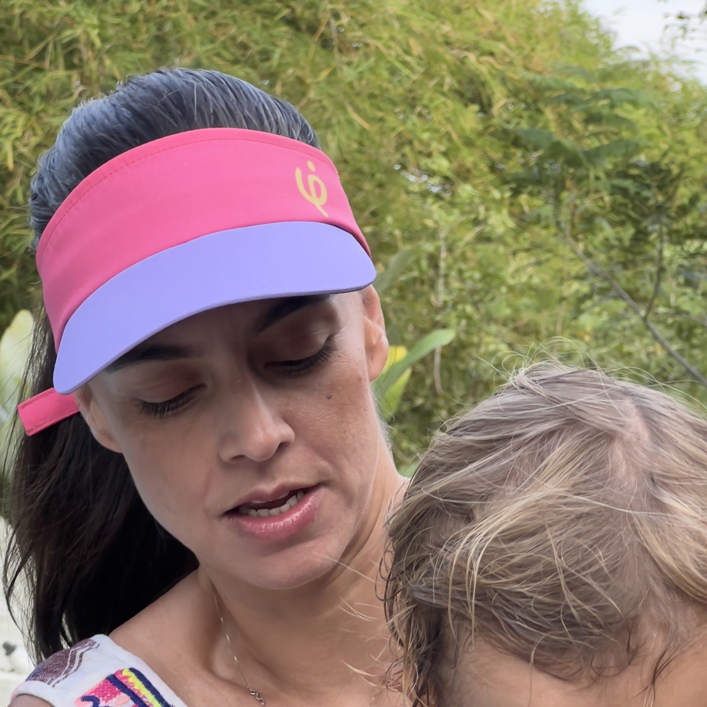 Mujer deportista  usa la visera bicolor fucsia y lavanda Frouros, protección solar ergonómica para entrenamiento de alto rendimiento.