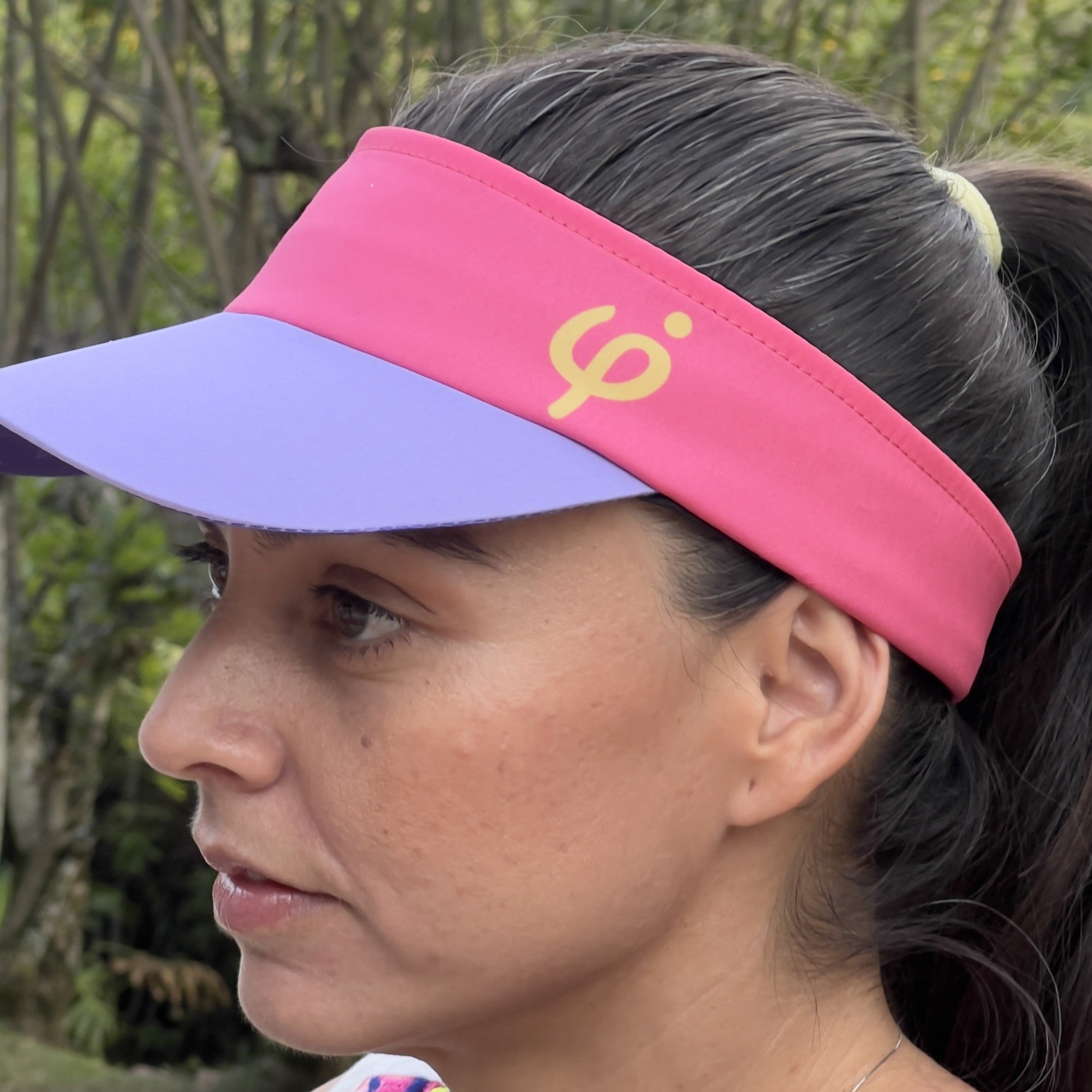 Vista lateral de una mujer  usando la visera deportiva fucsia Frouros, mostrando el ajuste cómodo y la transpirabilidad en exteriores.
